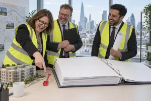 Three laughing fictional planning officials in high visibility jackets inspect a blank development folder and model homes
