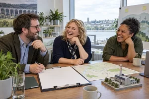 Three fictional adult regional innovation planners laughing around a large blank clipboard and a map.