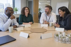 Four fictional public sector managers laughing around a blank hub and spoke model in an office
