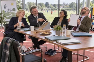 Four fictional taskforce members laugh around a conference table on a running track, proudly pointing at a miniature staircase while trainers remain untouched.