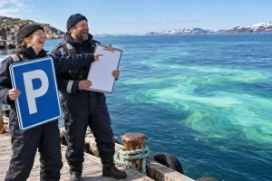 Two fictional Arctic navigation officials laughing while holding a parking permit beside a luminous Barents Sea bloom.