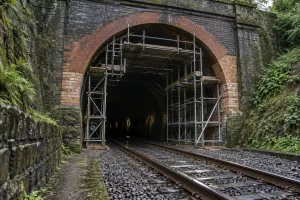 Scaffolding supports the arched entrance of a Victorian brick railway tunnel under restoration.