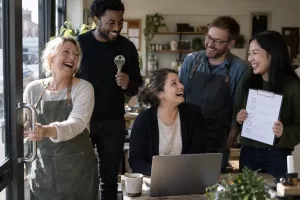 Five laughing adult small-business colleagues secure a shop office door and laptop.