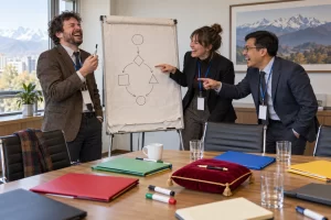 Three fictional conference delegates laugh around a flip chart with an abstract flowchart.