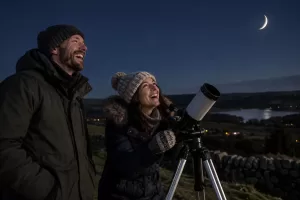 Two laughing astronomers with a telescope beneath a crescent moon using a crescent moon visibility map