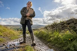 Original editorial photograph of a laughing rural resident in Wellington boots with a clipboard for Future Rural England report
