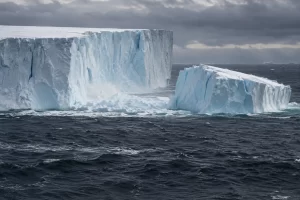 A newly separated slab of pale blue ice floats beside a colossal Antarctic iceberg in dark choppy ocean water.