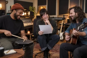 Laughing musicians in a recording studio holding an unreadable blank invoice sheet