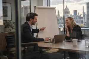 Two laughing consultants in a fictional Professional and Business Services Council co-chair 2026 meeting