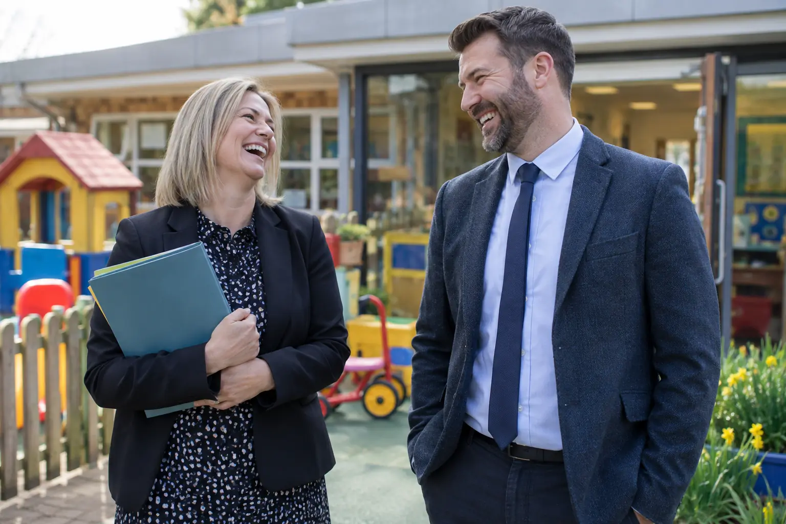 Two laughing school administrators outside a generic new school nursery