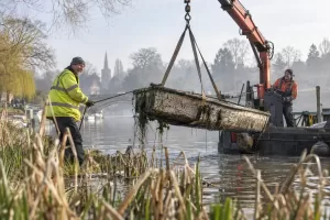 Laughing workers lifting an abandoned boat from the Upper Thames with a crane barge